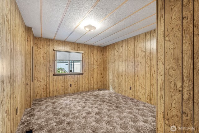 7300 32nd Ave NE Unit 5, Olympia, WA 98516 - spare room featuring a textured ceiling, carpet flooring, and wood walls