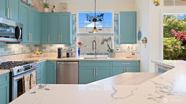 221 NE Honey Locust Ct, Poulsbo, WA 98370 - kitchen with appliances with stainless steel finishes, a sink, crown molding, backsplash, and hanging light fixtures