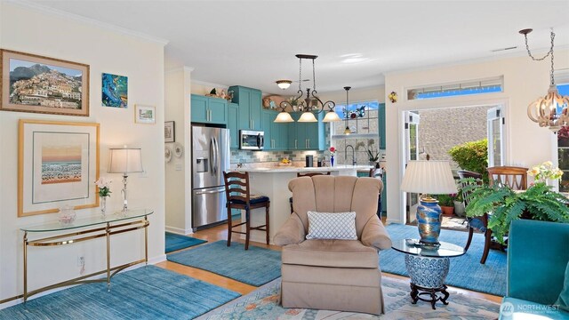 221 NE Honey Locust Ct, Poulsbo, WA 98370 - living area featuring a chandelier, light wood-style floors, ornamental molding, and baseboards