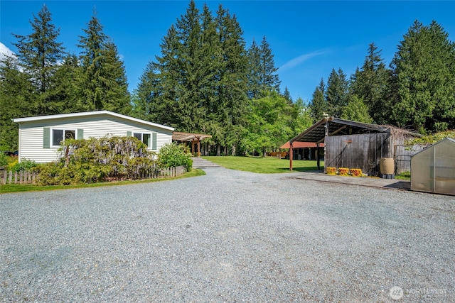 20800 Hartry Ln, Sedro Woolley, WA 98284 - view of side of property featuring a carport, gravel driveway, a lawn, an outbuilding, and a greenhouse