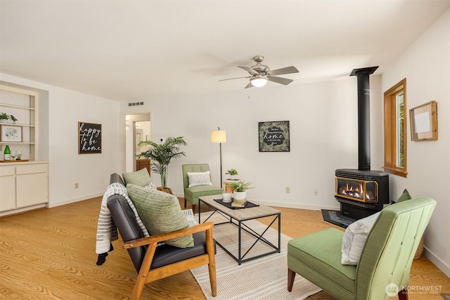 32227 Old Hansville Rd NE, Kingston, WA 98346 - living room featuring a wood stove, ceiling fan, light wood finished floors, and baseboards