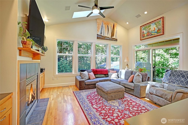 1577 Arrowhead Beach Rd, Camano Island, WA 98282 - living room featuring a fireplace, a ceiling fan, high vaulted ceiling, a skylight, and light wood-style flooring