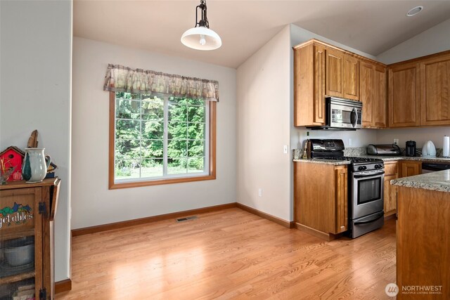 3210 275th St NE, Arlington, WA 98223 - kitchen featuring appliances with stainless steel finishes, light wood-style floors, brown cabinetry, light stone counters, and lofted ceiling