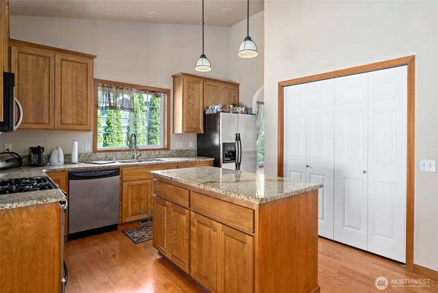 3210 275th St NE, Arlington, WA 98223 - kitchen with stainless steel appliances, a high ceiling, a sink, light wood-style flooring, and light stone counters