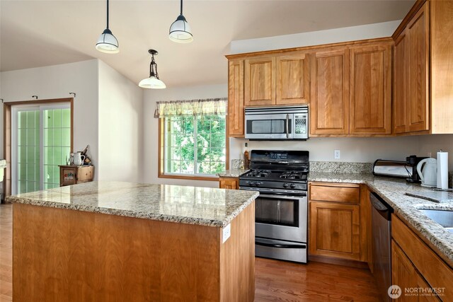 3210 275th St NE, Arlington, WA 98223 - kitchen featuring stainless steel appliances, wood finished floors, light stone counters, and brown cabinetry