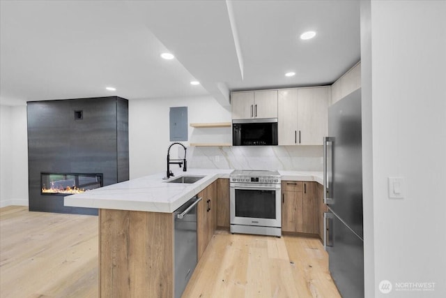 12816 130th Ct NE, Kirkland, WA 98034 - kitchen featuring stainless steel appliances, a sink, a peninsula, a fireplace, and light wood finished floors