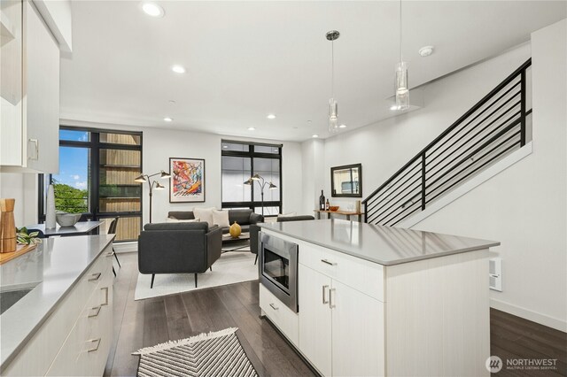 3219 California Ave SW Unit B, Seattle, WA 98116 - kitchen featuring stainless steel microwave, dark wood-style flooring, white cabinetry, a center island, and recessed lighting
