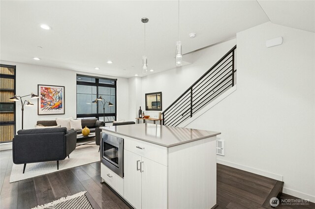 3219 California Ave SW Unit B, Seattle, WA 98116 - kitchen featuring stainless steel microwave, a kitchen island, white cabinetry, pendant lighting, and dark wood finished floors
