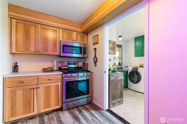 405 E Wiser Lake Rd, Lynden, WA 98264 - kitchen featuring stainless steel appliances, washer / clothes dryer, light countertops, a textured ceiling, and wood finished floors