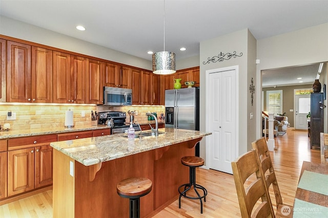 7623 152nd St SE, Snohomish, WA 98296 - kitchen featuring appliances with stainless steel finishes, light wood-style flooring, light stone countertops, a sink, and recessed lighting