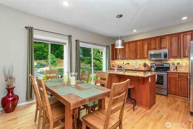 7623 152nd St SE, Snohomish, WA 98296 - kitchen with appliances with stainless steel finishes, light wood-style floors, brown cabinetry, backsplash, and light stone countertops