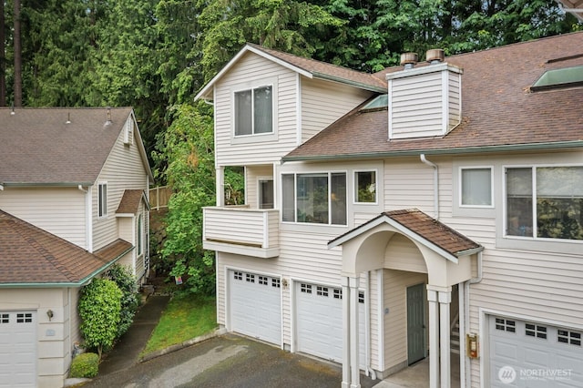 8828 238th St SW Unit D-1, Edmonds, WA 98026 - view of front facade with driveway, a garage, roof with shingles, a balcony, and a chimney