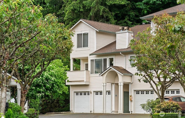 8828 238th St SW Unit D-1, Edmonds, WA 98026 - view of front of house featuring a garage, a balcony, driveway, roof with shingles, and a chimney