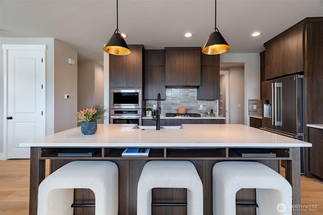 14524 204th Ave E Unit 893, Bonney Lake, WA 98391 - kitchen with appliances with stainless steel finishes, dark brown cabinetry, light wood-type flooring, light countertops, and recessed lighting