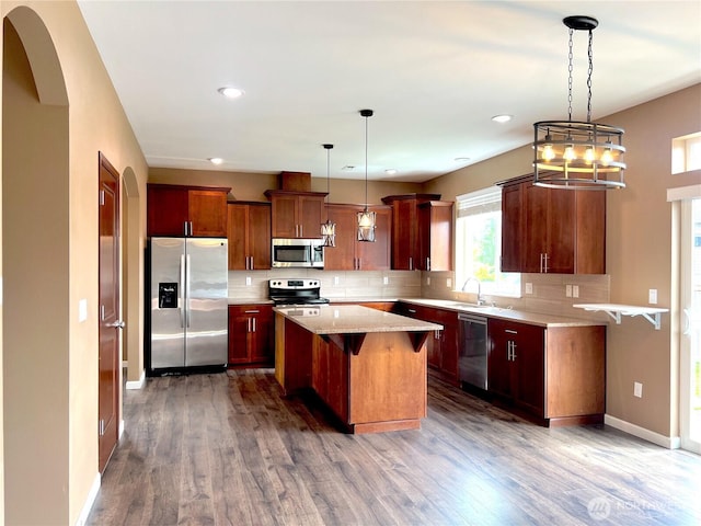 10027 SE Dotson St SE, Yelm, WA 98597 - kitchen featuring stainless steel appliances, decorative backsplash, wood finished floors, a kitchen island, and a sink