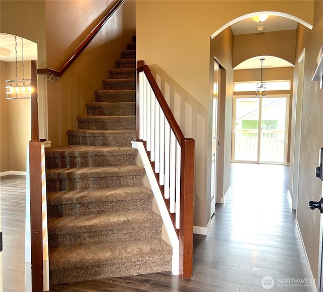 10027 SE Dotson St SE, Yelm, WA 98597 - staircase with wood finished floors, a high ceiling, baseboards, and arched walkways