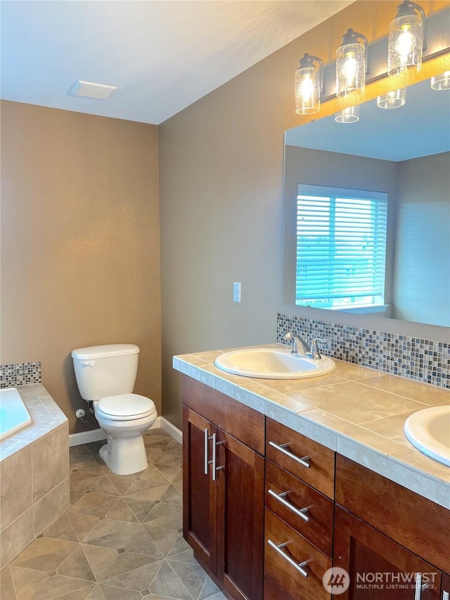 10027 SE Dotson St SE, Yelm, WA 98597 - bathroom with tiled tub, toilet, double vanity, tile patterned flooring, and baseboards