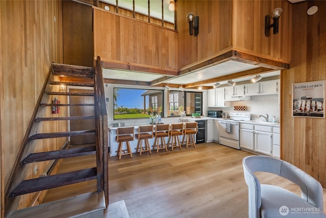 4489 Sucia Dr, Ferndale, WA 98248 - kitchen featuring white electric range, wooden walls, light countertops, a sink, and light wood-style flooring