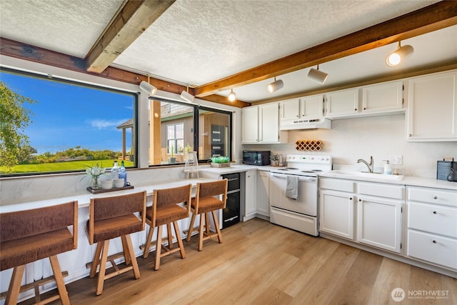4489 Sucia Dr, Ferndale, WA 98248 - kitchen featuring electric range, under cabinet range hood, a sink, black microwave, and beam ceiling