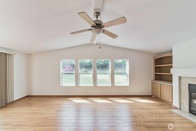 824 Cherub Pl E, Port Orchard, WA 98366 - unfurnished living room featuring vaulted ceiling, light wood-type flooring, a tiled fireplace, a ceiling fan, and baseboards