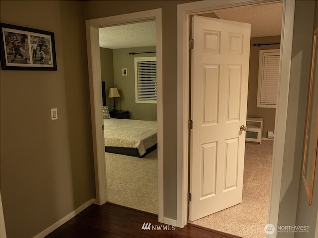 12840 SE 40th Ct Unit B12, Bellevue, WA 98006 - hallway featuring dark carpet, baseboards, a textured ceiling, and dark wood-type flooring