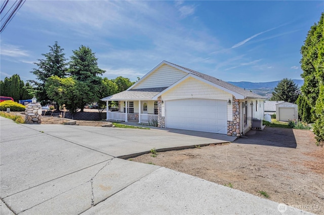 1718 6th St SE, East Wenatchee, WA 98802 - view of front of house featuring covered porch, a garage, concrete driveway, stone siding, and a mountain view