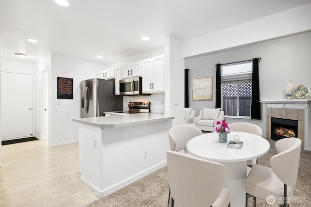 8906 161st St E, Puyallup, WA 98375 - kitchen featuring appliances with stainless steel finishes, white cabinets, a tile fireplace, recessed lighting, and light countertops