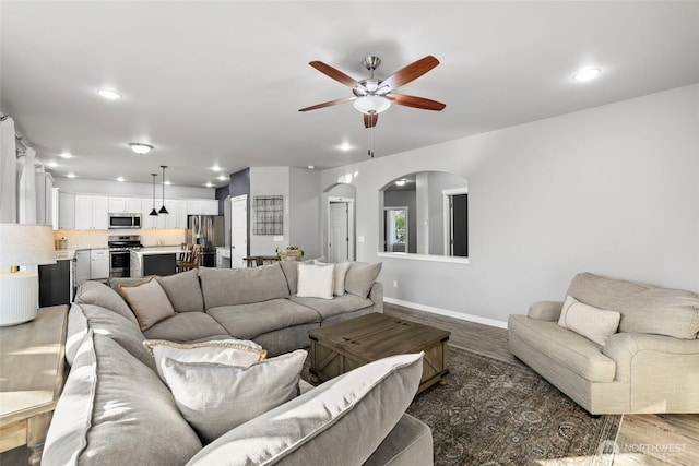 10713 Palisades St SE, Yelm, WA 98597 - living room with arched walkways, a ceiling fan, light wood-style floors, recessed lighting, and baseboards