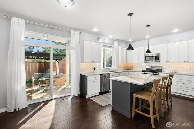 10713 Palisades St SE, Yelm, WA 98597 - kitchen featuring stainless steel appliances, white cabinetry, a kitchen island, light stone countertops, and a sink