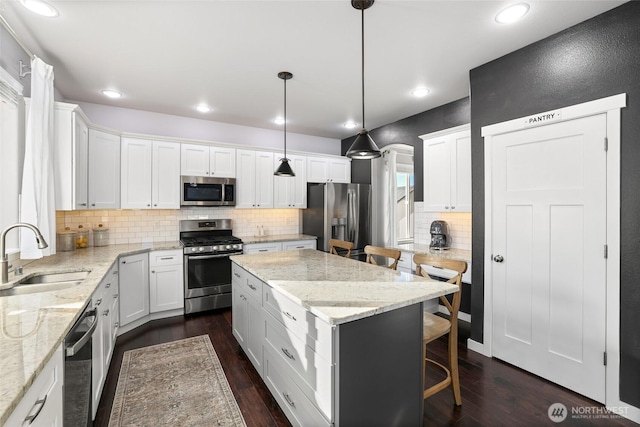 10713 Palisades St SE, Yelm, WA 98597 - kitchen with appliances with stainless steel finishes, a sink, tasteful backsplash, a kitchen breakfast bar, and white cabinets