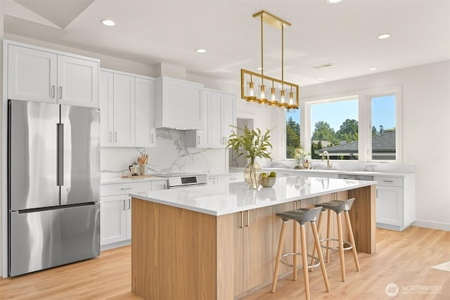 5425 Salish Rd, Blaine, WA 98230 - kitchen featuring stainless steel fridge, light wood-style flooring, light countertops, tasteful backsplash, and a center island