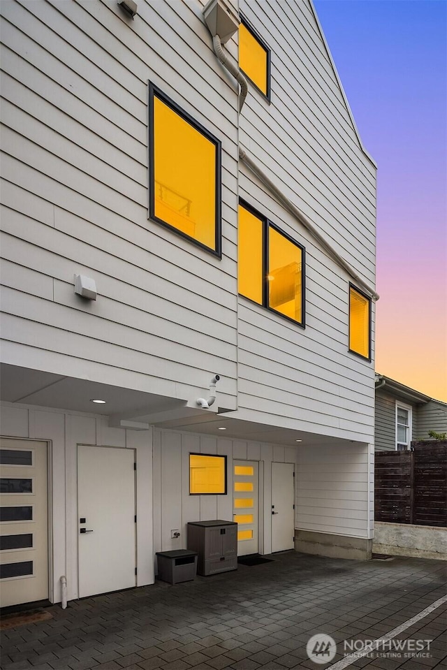 3852 Beach Dr SW Unit A, Seattle, WA 98116 - property exterior at dusk featuring board and batten siding and a patio