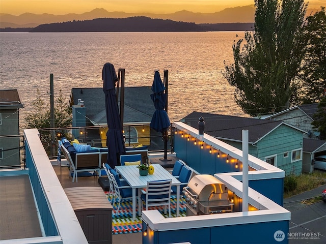 3852 Beach Dr SW Unit A, Seattle, WA 98116 - deck at dusk with a water and mountain view, area for grilling, and an outdoor living space