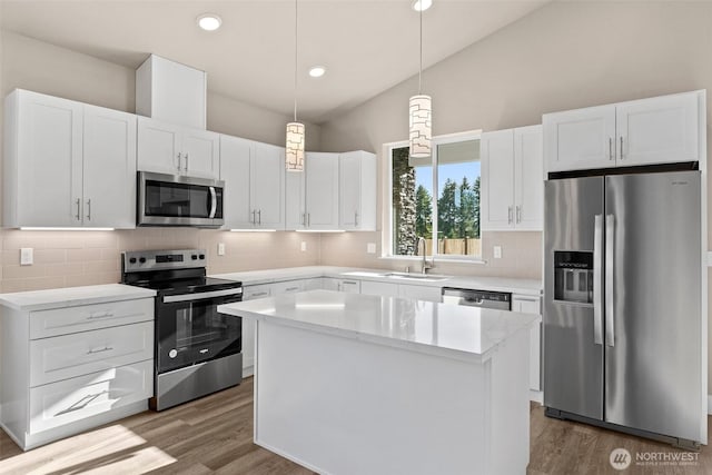 2114 Hawks View Ln, Winlock, WA 98596 - kitchen featuring stainless steel appliances, vaulted ceiling, wood finished floors, a sink, and a center island