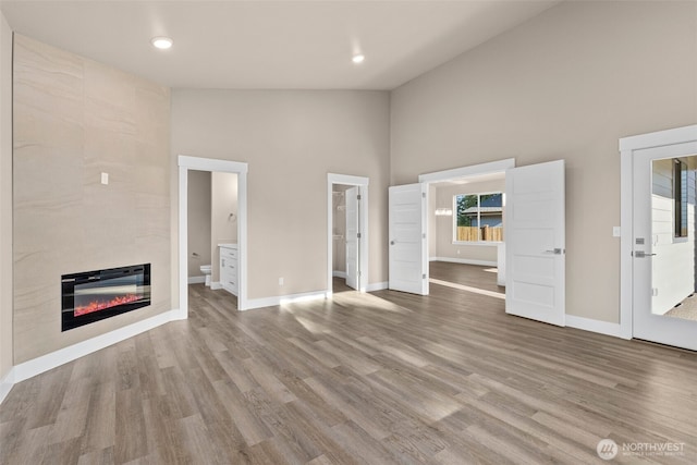 2114 Hawks View Ln, Winlock, WA 98596 - unfurnished living room featuring high vaulted ceiling, wood finished floors, baseboards, and a tile fireplace