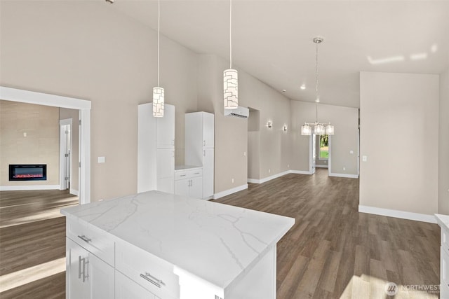 2120 Hawks View Ln, Winlock, WA 98596 - kitchen featuring open floor plan, dark wood finished floors, a glass covered fireplace, high vaulted ceiling, and pendant lighting