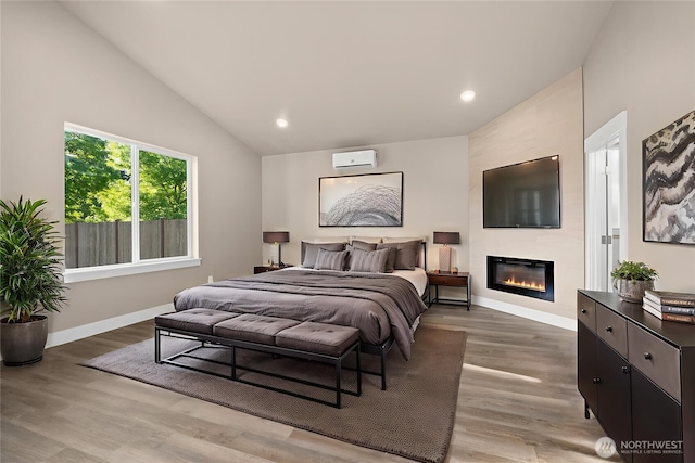 2120 Hawks View Ln, Winlock, WA 98596 - bedroom featuring lofted ceiling, a fireplace, a wall unit AC, light wood-style flooring, and baseboards