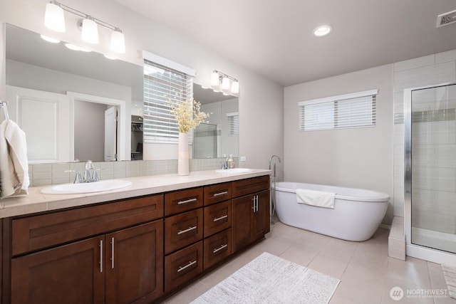 8223 31st Street Ct E, Edgewood, WA 98371 - bathroom with double vanity, a shower stall, a freestanding bath, tile patterned floors, and tasteful backsplash
