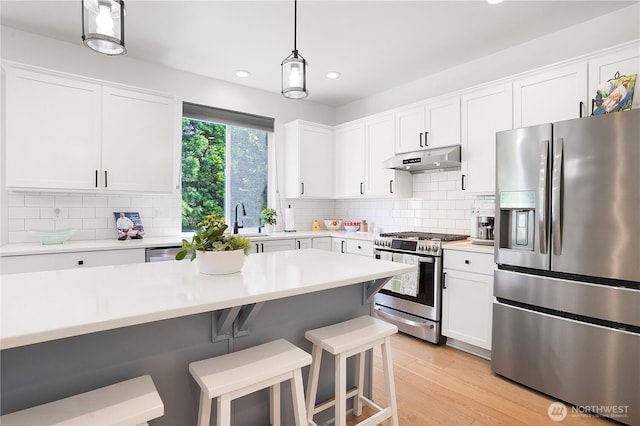 7118 Ashdown Ln SE, Olympia, WA 98513 - kitchen with appliances with stainless steel finishes, under cabinet range hood, recessed lighting, a breakfast bar, and light countertops