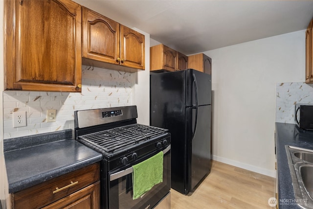 1704 27th Ave, Seattle, WA 98122 - kitchen featuring black appliances, dark countertops, tasteful backsplash, and brown cabinetry