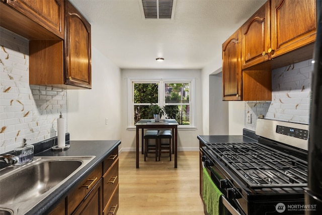 1704 27th Ave, Seattle, WA 98122 - kitchen featuring gas stove, a sink, decorative backsplash, and dark countertops