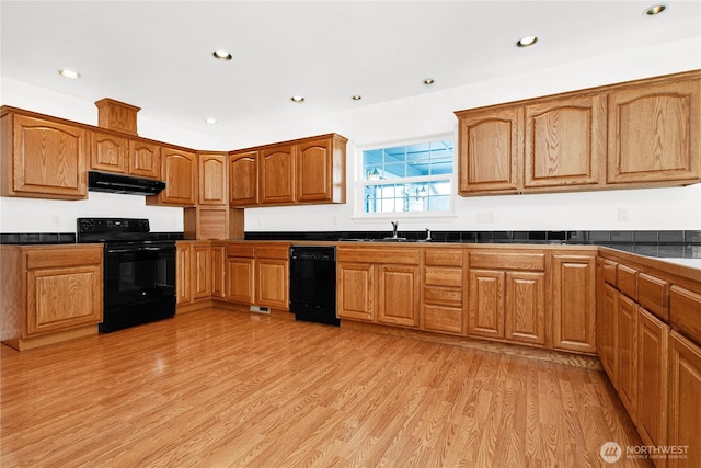 514 Mckinley Ave, Raymond, WA 98577 - kitchen featuring black appliances, under cabinet range hood, dark countertops, a sink, and light wood-type flooring