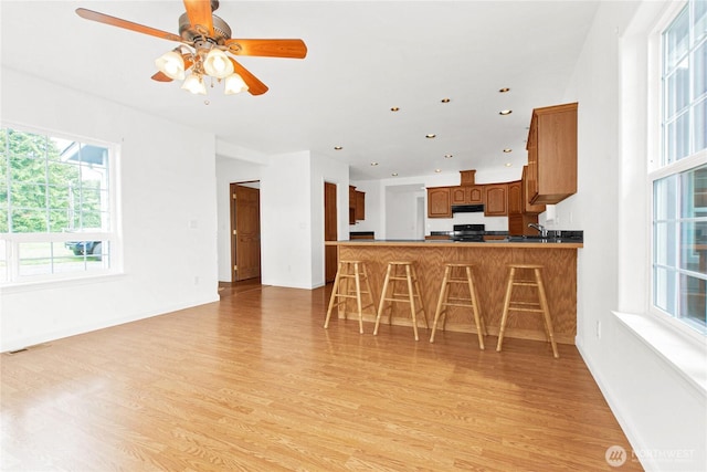 514 Mckinley Ave, Raymond, WA 98577 - kitchen featuring range hood, light wood finished floors, black stove, brown cabinets, and recessed lighting