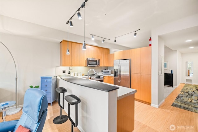17 W Mercer St Unit 206, Seattle, WA 98119 - kitchen with appliances with stainless steel finishes, a peninsula, light wood-type flooring, a kitchen bar, and hanging light fixtures