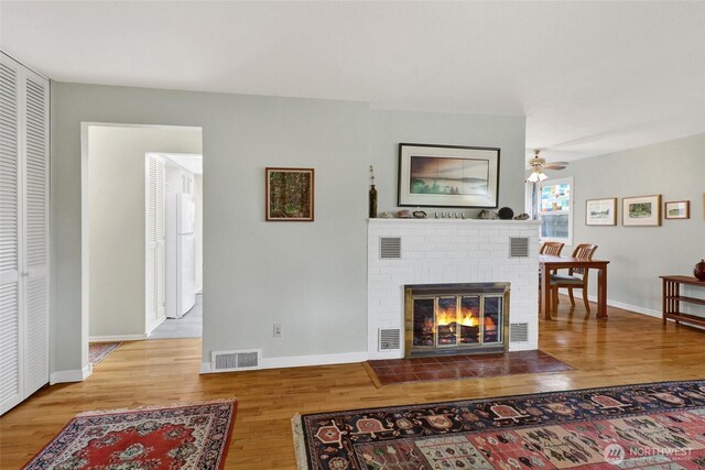 2708 Lynn St, Bellingham, WA 98225 - living room featuring wood finished floors, a brick fireplace, ceiling fan, and baseboards