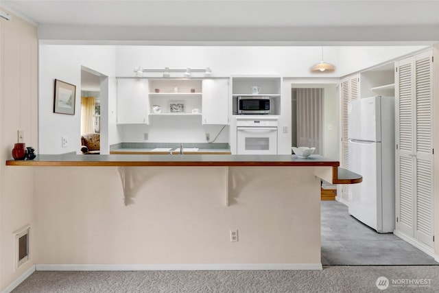 2708 Lynn St, Bellingham, WA 98225 - kitchen with white appliances, open shelves, a breakfast bar area, white cabinetry, and a sink