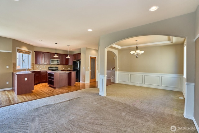 27006 229th Pl SE, Maple Valley, WA 98038 - kitchen featuring stainless steel appliances, arched walkways, open floor plan, light colored carpet, and wainscoting