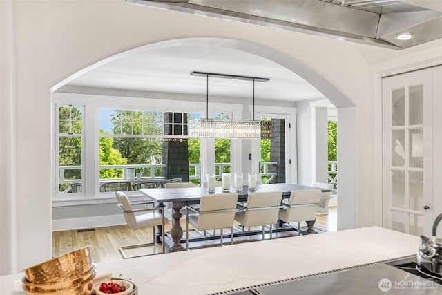 1542 Grand Ave, Seattle, WA 98122 - dining room featuring arched walkways, healthy amount of natural light, a chandelier, and wood finished floors