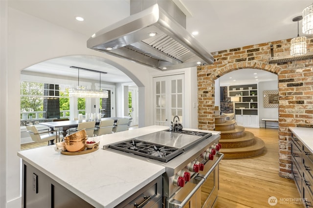 1542 Grand Ave, Seattle, WA 98122 - kitchen with arched walkways, island exhaust hood, light wood-style floors, double oven range, and hanging light fixtures