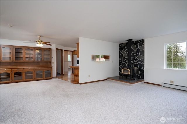 818 295th St E, Roy, WA 98580 - unfurnished living room with carpet flooring, baseboard heating, a wood stove, and baseboards